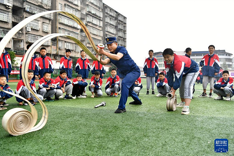5月10日，在四川省广安市前锋区代市实验学校，消防队员在给学生演示抛消防水带。（新华社发 张启富摄）.jpg
